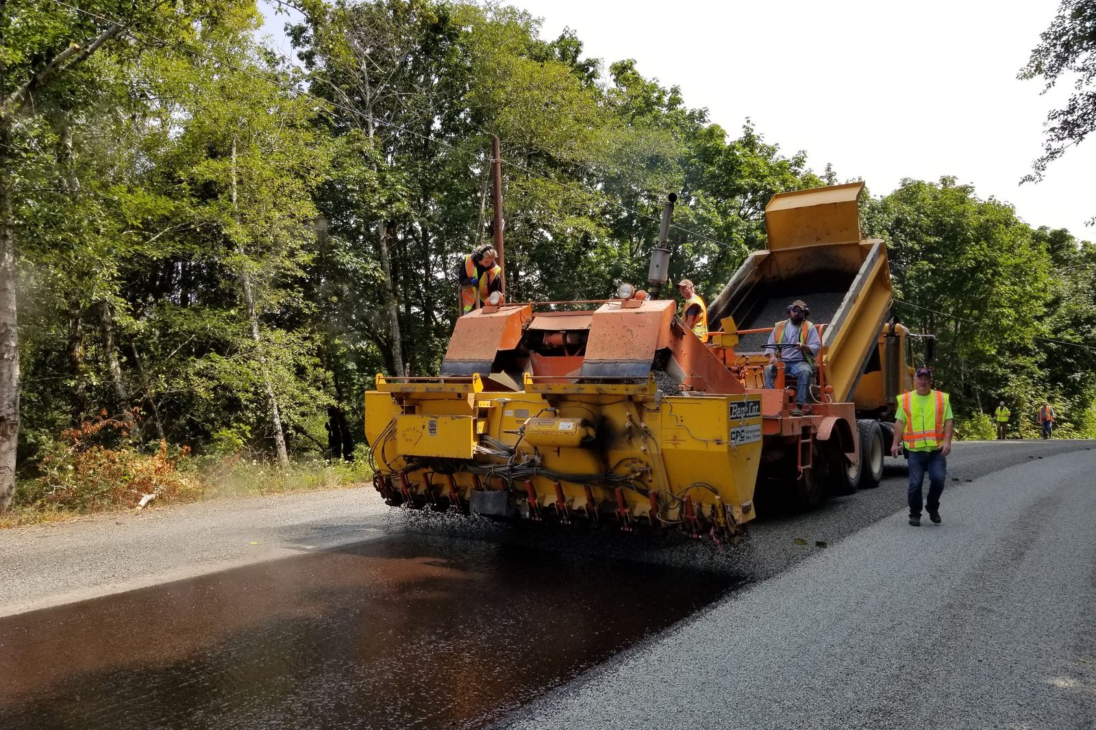 Paving crew laying hot asphalt, an example of the driveway work we do