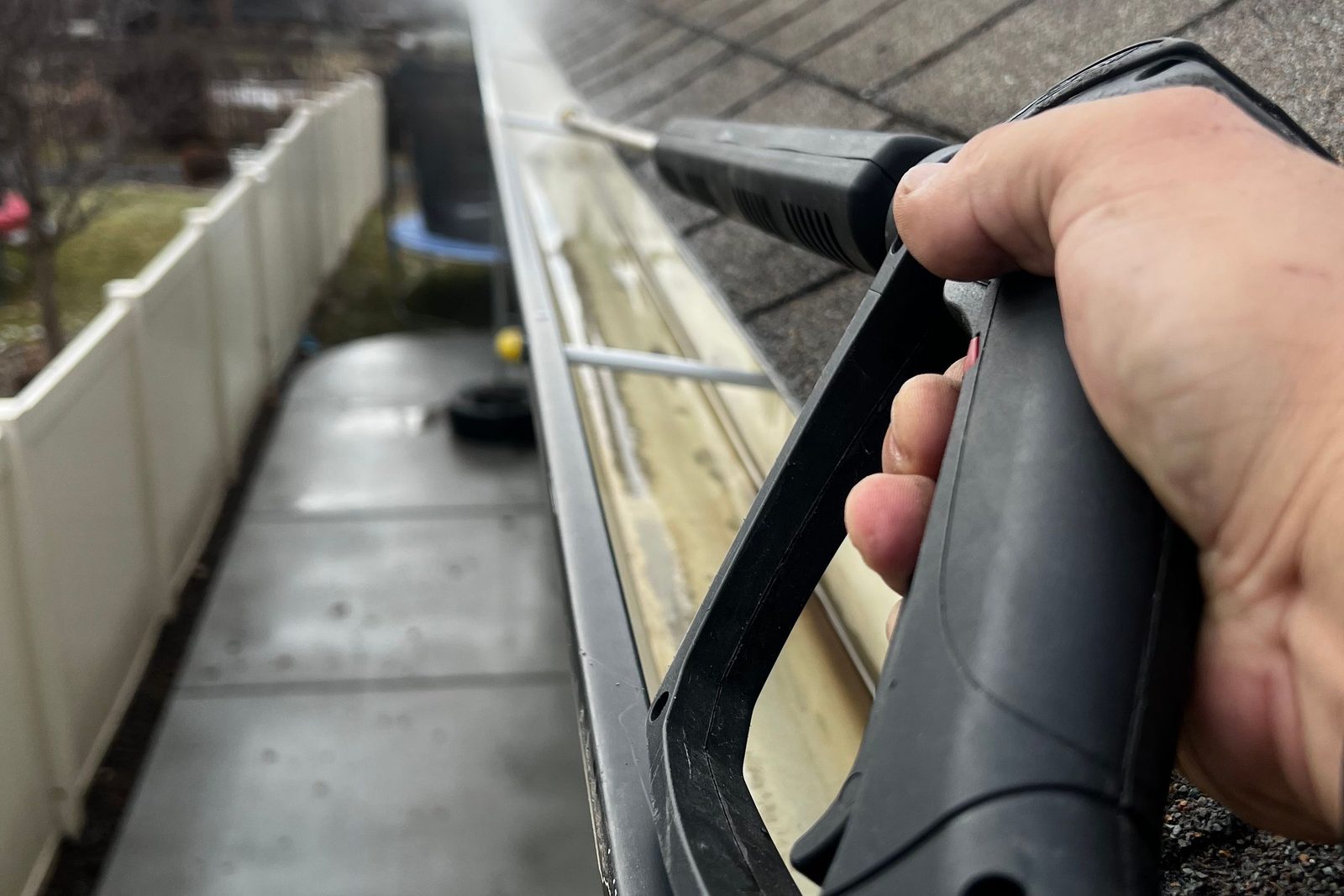 Gutter being flushed clean along a roofline, an example of gutter cleanouts